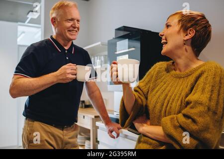 Smiling mature man and woman having coffee break in office. Happy colleagues taking a break from work in office. Stock Photo
