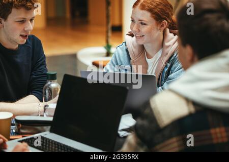 Students doing studies around table in high school campus. Young people at university working on project while sitting at table. Stock Photo
