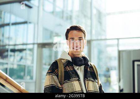 Young man standing at stairs and smiling in college. Boy in casual wear looking at camera while at high school campus. Stock Photo