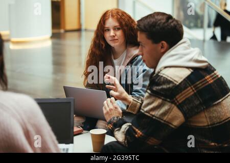 Students in group study at university campus. Young man at high school explaining something to his friends. Stock Photo