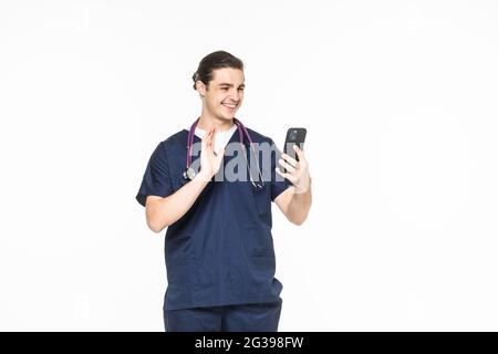Medicine, healthcare and technology concept. Happy smiling doctor or male nurse in blue uniform with stethoscope having video call on phone over white Stock Photo