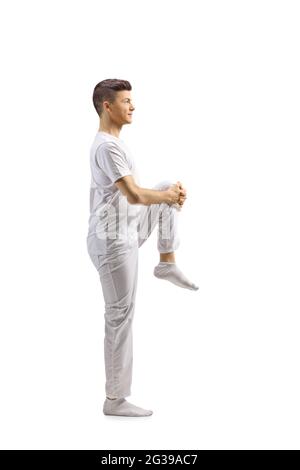 Full length profile shot of a guy in white clothes streching leg isolated on white background Stock Photo