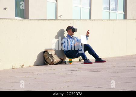 Businessman examining virtual reality simulator while using laptop in park Stock Photo