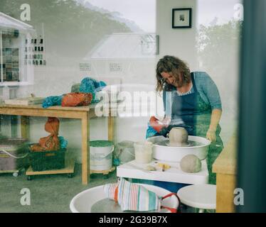 woman drying clay on a pottery wheel in her home studio in the UK Stock Photo