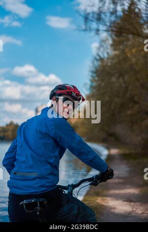 Man wearing bicycle helmet standing in forest, spending free vacation time on a bicycle trip in a forest. Stock Photo