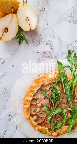 Cutted pears and pear and gorgonzola cheese galette with green rucola Stock Photo