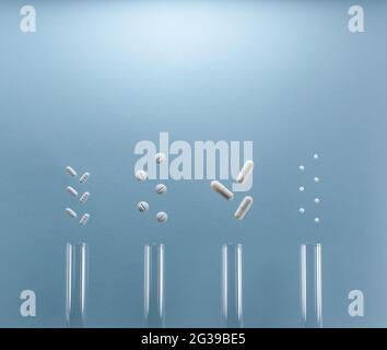 Medical test tubes with various white tablets, pills, pellets, capsules. On a blue background. Flat lay. Stock Photo