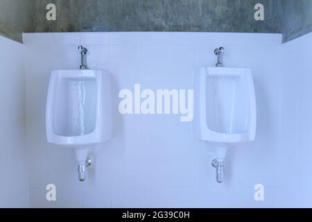 White urinals in men public toilet. Ceramic urinals in a row Stock Photo