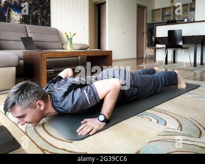 A man pushes off from the floor doing sports at home Stock Photo
