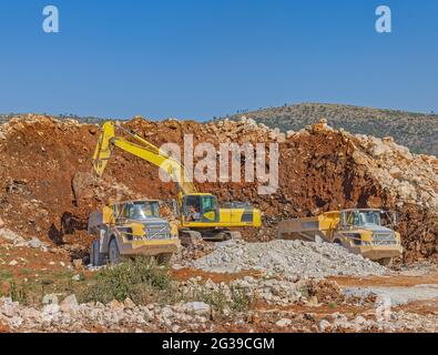 Excavator and trucks at a road construction site Stock Photo