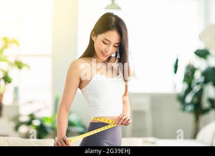 young woman  confidently measured her waist circumference, satisfied with her posture, and very happy to lose weight Stock Photo