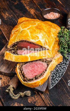 Homemade Beef Wellington puff pie with tenderloin meat on a cutting board. Dark wooden background. Top view Stock Photo