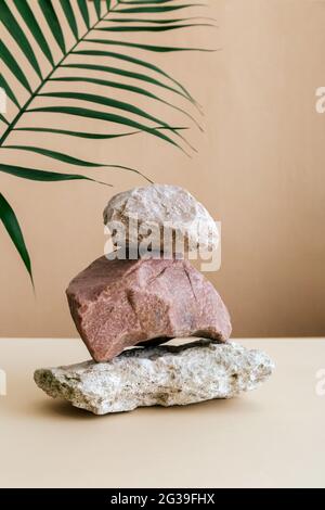 Empty Podium Stones tower on kraft brown paper background. Stones pedestal display on beige background made from seashell stones Palm leaf. Abstract Stock Photo