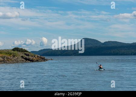 A man is kayaking on East Sound at the village of Eastsound, on Orcas Island in the San Juan Islands in Washington State, United States. Stock Photo