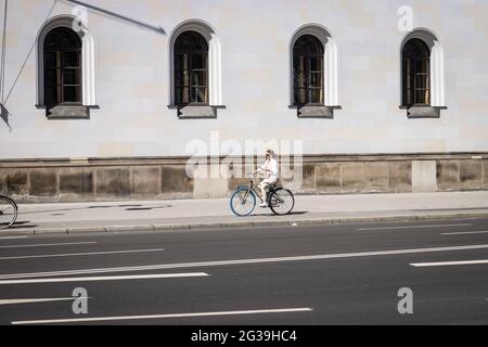 MUNICH, GERMANY - Jun 12, 2021: Woman riding her bike while looking on her phone, chatting while riding Stock Photo