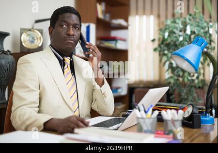 African american executive having phone conversation at office table Stock Photo