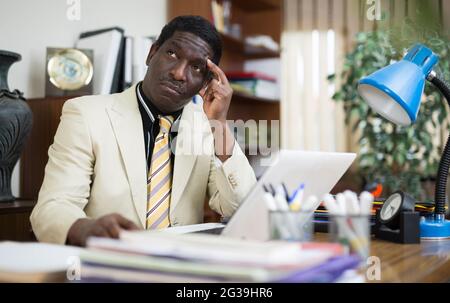 Pensive african american man working in modern office Stock Photo
