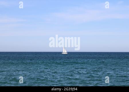 Lone white sailboat on open sea Stock Photo