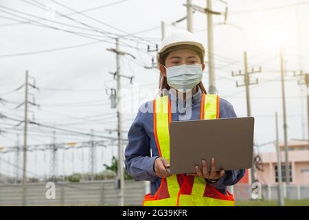 Female Engineer holding laptop working outdoor. Worker Woman use computer technology Stock Photo
