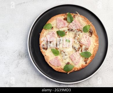 Tortilla with cheese, mushrooms and ham on a round plate on a light gray background. Top view, flat lay Stock Photo