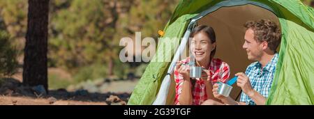Camping couple eating food in tent on summer travel camp holiday banner panoramic. Interracial friends having fun relaxing in the sun with outdoor Stock Photo
