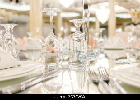 Mirror table festive setting in luxury restaurant, close up view. Glasses, plates, cutlery on mirror table. Selective soft focus, shallow depth of field Stock Photo