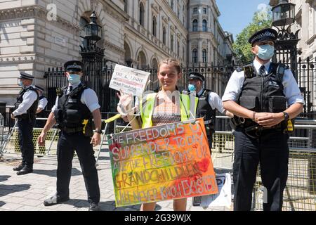 London, UK. 14th June, 2021. Anti-lockdown protestor holds a placard along Downing street in front of on-duty police officers during the demonstration.UK Prime Minister Boris Johnson is due to make an announcement regarding the extension of the lockdown regulations in the UK. Protestors gathered outside Downing Street at 12pm to protest against the extension, on the grounds that it is a violation of human rights and various freedoms. They also protested against wearing masks and being subjected to the vaccination program. Credit: SOPA Images Limited/Alamy Live News Stock Photo