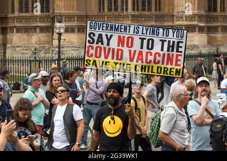 London, UK. 14th June, 2021. Anti-lockdown protestor holds a placard that says Government is lying to you, Say No to the COVID vaccine. Save the children during the demonstration.UK Prime Minister Boris Johnson is due to make an announcement regarding the extension of the lockdown regulations in the UK. Protestors gathered outside Downing Street at 12pm to protest against the extension, on the grounds that it is a violation of human rights and various freedoms. They also protested against wearing masks and being subjected to the vaccination program. Credit: SOPA Images Limited/Alamy Live News Stock Photo