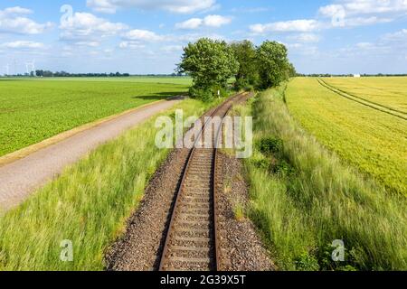 Wanzleben, Germany. 13th June, 2021. An old railway track runs past freshly tilled fields. (Shot with a drone) Credit: Stephan Schulz/dpa-Zentralbild/ZB/dpa/Alamy Live News Stock Photo