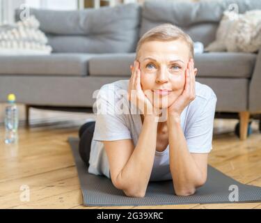 Senior woman smiling at camera while exercising at home Stock Photo