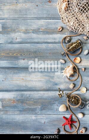 Summer interior decoration with starfishes, seashells, ropes and bottles with stones on blue wooden background. Copy space. Still life. Flat lay Stock Photo