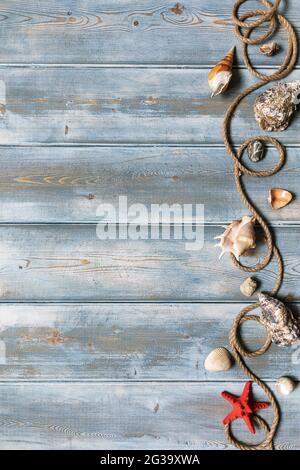 Summer interior decoration with starfishes, seashells, ropes and bottles with stones on blue wooden background. Copy space. Still life. Flat lay Stock Photo