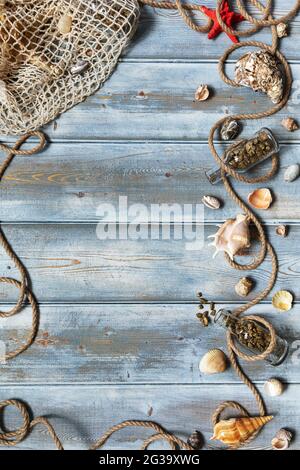 Summer interior decoration with starfishes, seashells, ropes and bottles with stones on blue wooden background. Copy space. Still life. Flat lay Stock Photo