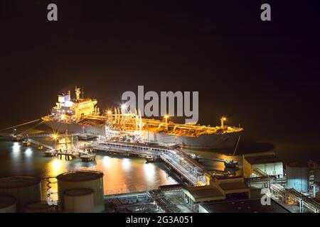 Night scene aerial view of big oil tanker ship loading at oil depot pier in power industry with copy space in Hong Kong Stock Photo