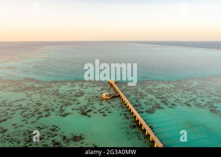 Sanganeb Reef National Park in Sudan, Red Sea, aerial view from Sanganeb Lighthouse with old wooden pier extending towards the sea, azure crystal wate Stock Photo