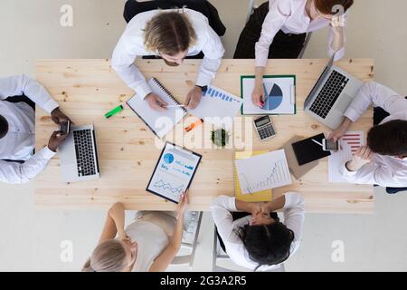 Business people brainstorming at office desk analyzing financial reports and pointing out financial data on a sheet, top view Stock Photo