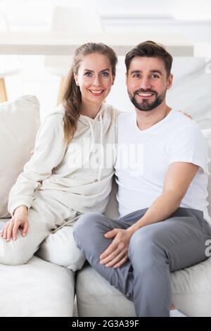 Portrait of mid adult couple relaxing in living room and smiling, looking at camera Stock Photo