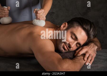 Young handsome man having back massage with pouche Stock Photo