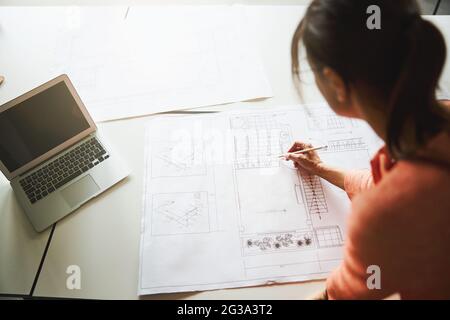 Beautiful elegant lady in pink clothes is working with blueprints in the working space Stock Photo