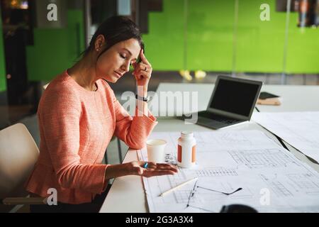 Beautiful Caucasian business analyst feeling headache while working with report in the office Stock Photo