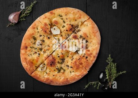 Focaccia with olives, garlic and thyme on black background Stock Photo