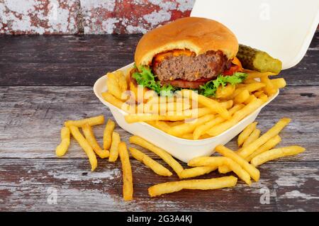 Cheeseburger and French fries in a take away box with pickled gherkin Stock Photo