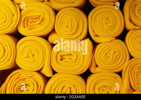 Twisted yellow blankets in a roll as background, home textile Stock Photo