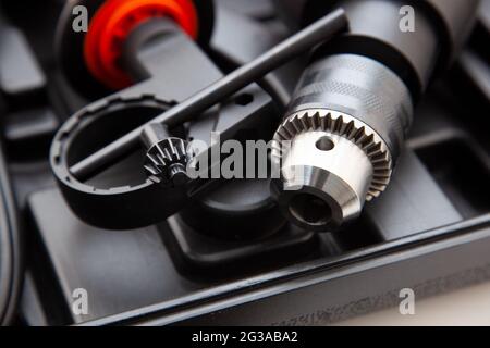Electric drill in a suitcase. Keyless chuck. Gear teeth. Close-up tool. Metal details. Worker mechanics and tools Stock Photo