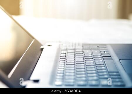 Opened black laptop, side view. Selective focus, sunlight backlight. Stock Photo