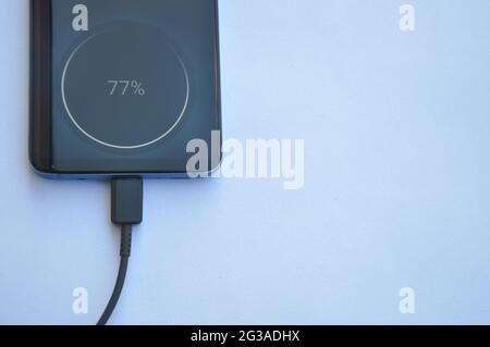Overhead view of a smartphone connected with USB Type-C charging cable with negative space, Mobile phone charging - Stock Photo Stock Photo