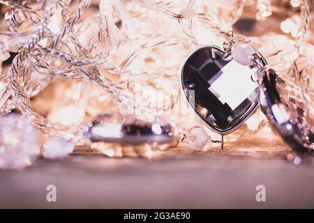 Heart shaped gem stones on golden lights of electric garland with bokeh Stock Photo