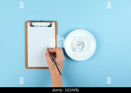 Intermittent fasting, ketogenic, diet concept. Plate with white alarm clock Stock Photo