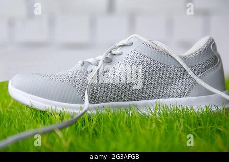 Sports shoes on the grass against a brick wall. Shoes for sports on the sports field made of lawn grass. Stock Photo