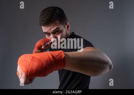 Young fighter performing left jab with hand wrapped in boxing tape Stock Photo